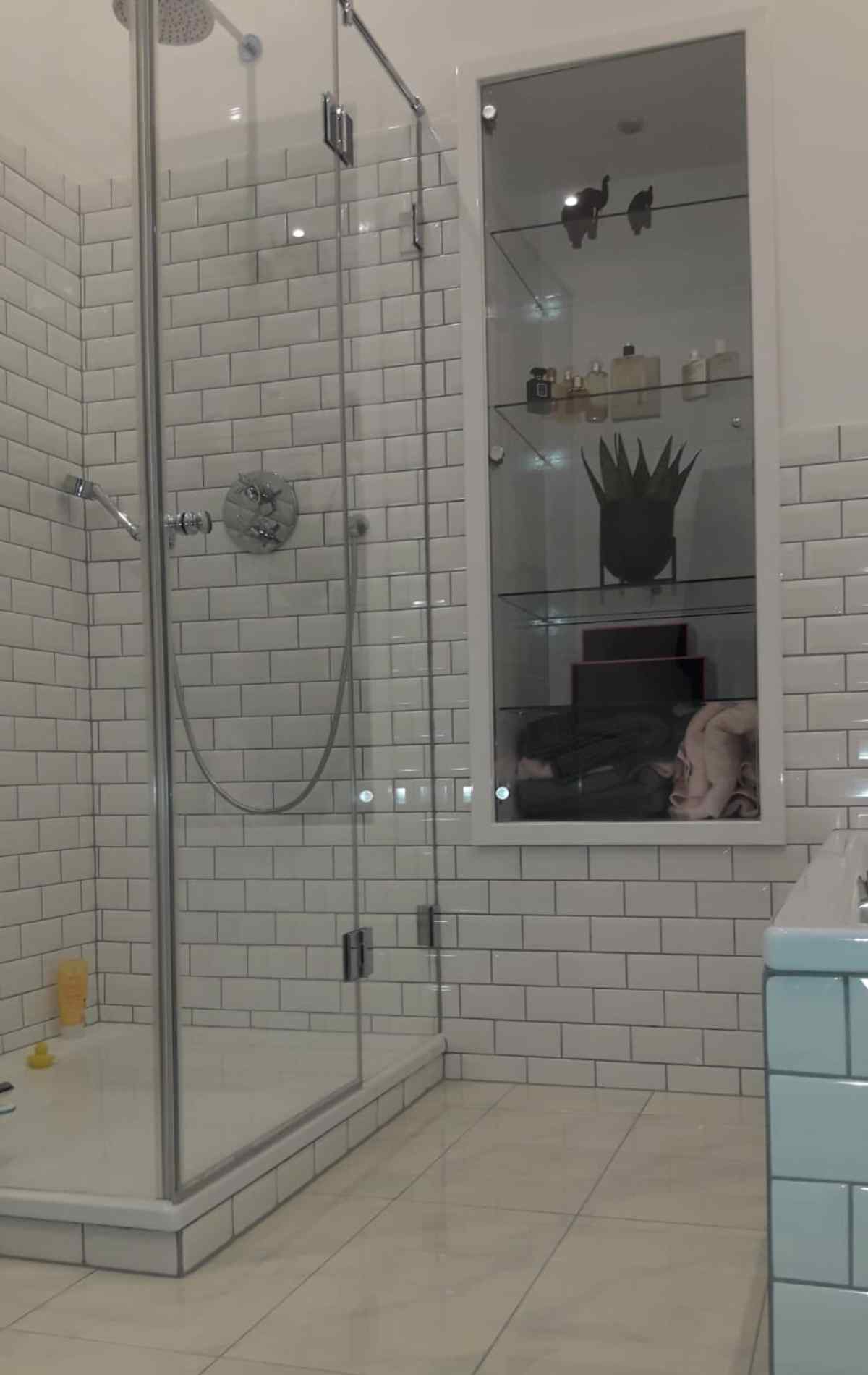 Schönes Bad mit weißen Metrofliesen und eingelassenem Wandregal