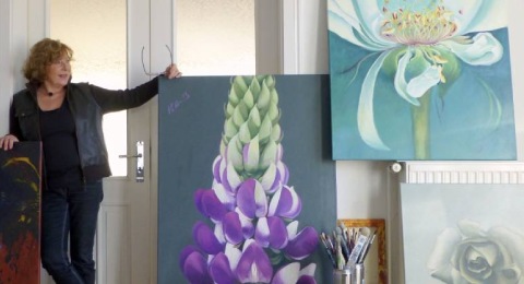 Künstlerin mit Bildern, auf denen sie eine Lupinie und Rosen verschiedenen Typs in Farbe festgehalten hat