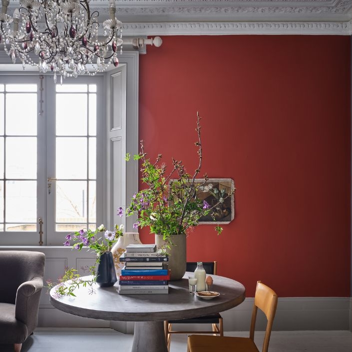 Ein warmes Rot abgesetzt von einer weißen Stuckdecke wirkt in diesem Raum elegant und beruhigend