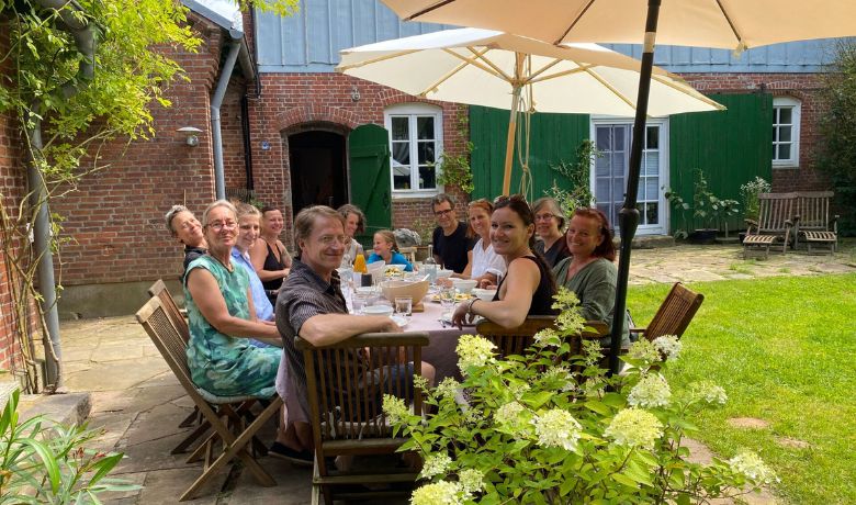 Teilnehmer eines Workshops essen und trinken vor der Tenne