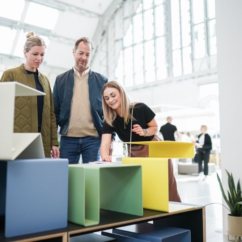 Eine Designerin stellt einem Paar auf der Blickfang Hamburg 2025 ihre Wohnidee vor